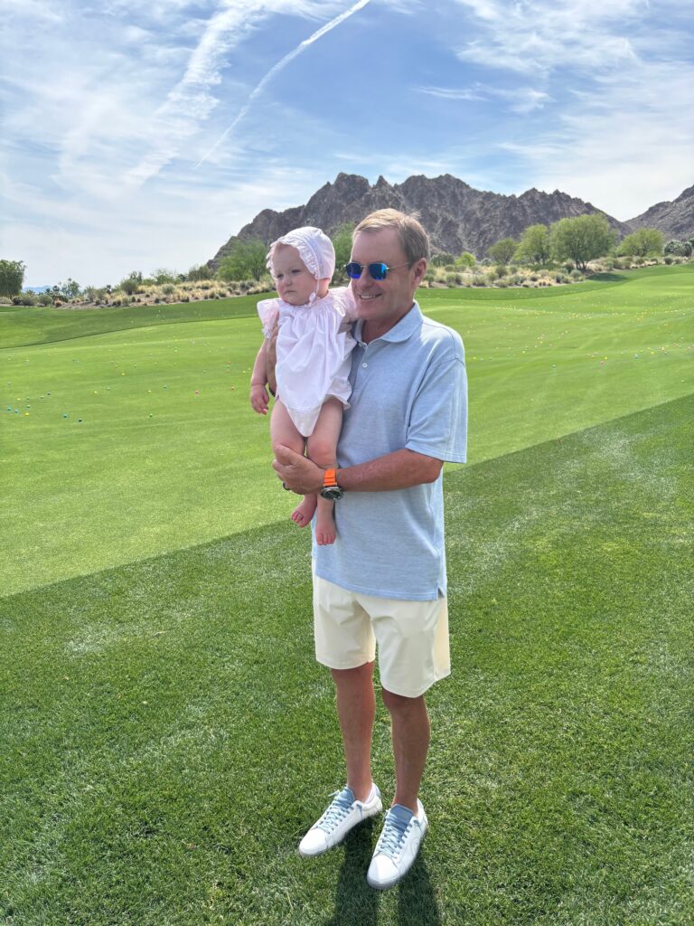 Devin Doyle Holding a Child on a Scenic Golf Course