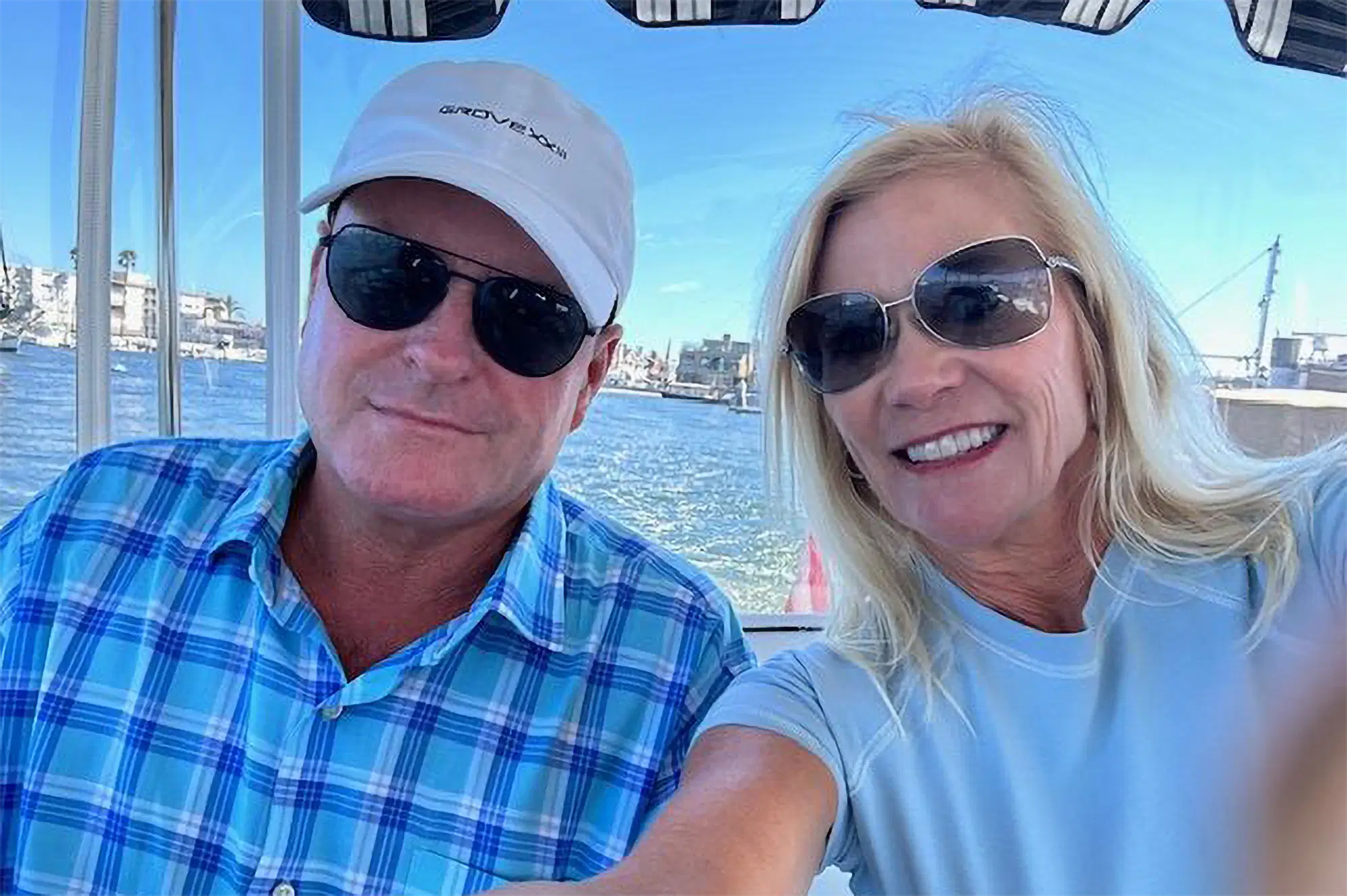 Devin Doyle and his wife smiling for a selfie aboard a boat near a waterfront marina
