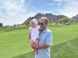 Devin Doyle holding a baby on a golf course