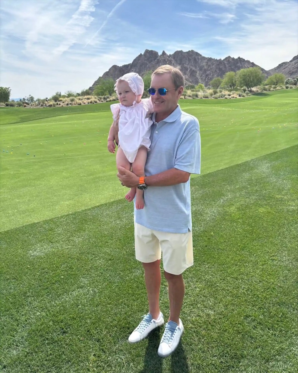 Devin Doyle holding a baby on a golf course